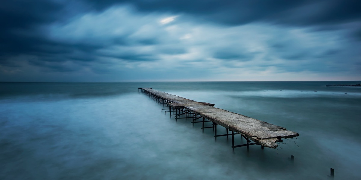 A wooden pier reaching into a still, grey sea